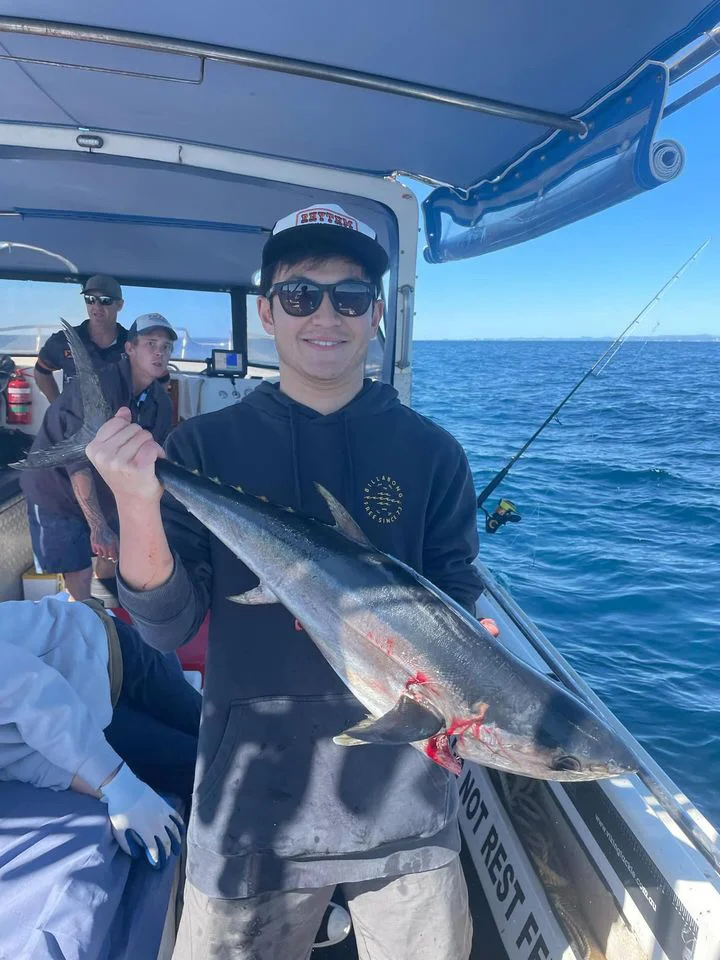 Shinya holding a large fish on a boat at sea.